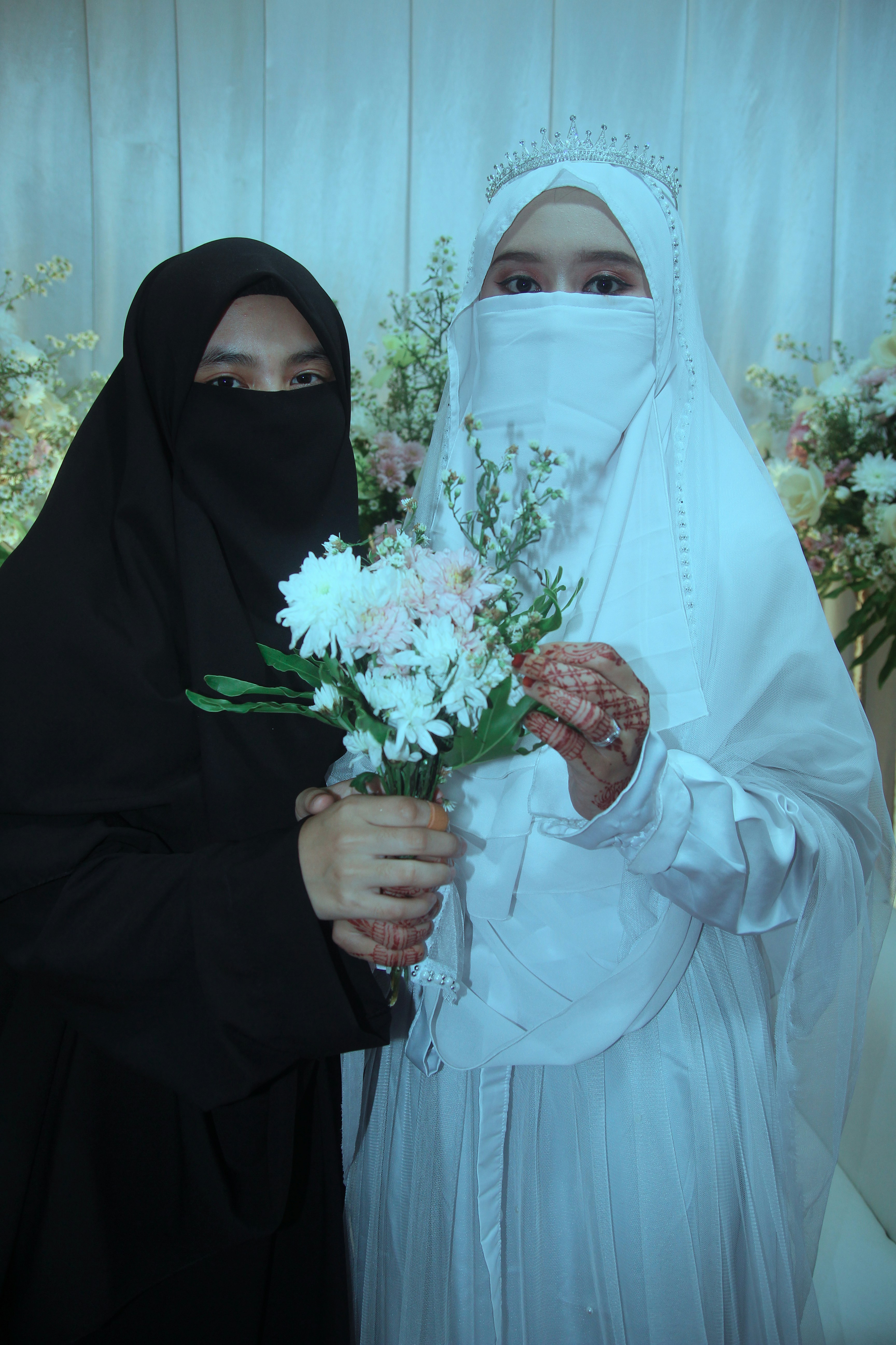 Dos mujeres con hiyab sosteniendo flores en sus manos