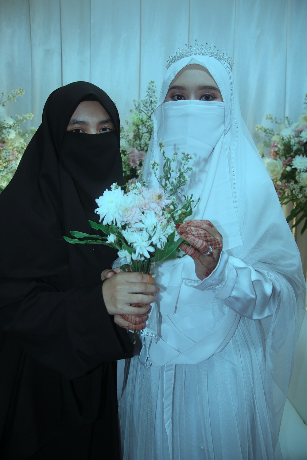 two women in hijabs holding flowers in their hands