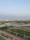 A serene urban landscape featuring high-rise buildings in the background, surrounded by lush greenery and calm water bodies. Solar panels are visible on the banks, indicating a focus on eco-friendly solutions. The area includes paved walkways and well-maintained roads, enhancing accessibility amidst a blend of natural and urban elements.