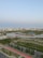 A serene urban landscape featuring high-rise buildings in the background, surrounded by lush greenery and calm water bodies. Solar panels are visible on the banks, indicating a focus on eco-friendly solutions. The area includes paved walkways and well-maintained roads, enhancing accessibility amidst a blend of natural and urban elements.
