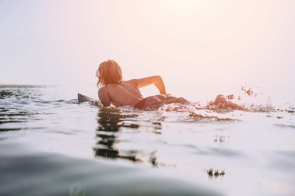 uma mulher deitada em uma prancha de surf no oceano