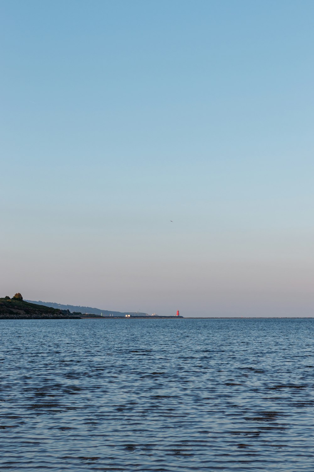 a large body of water with a lighthouse in the distance