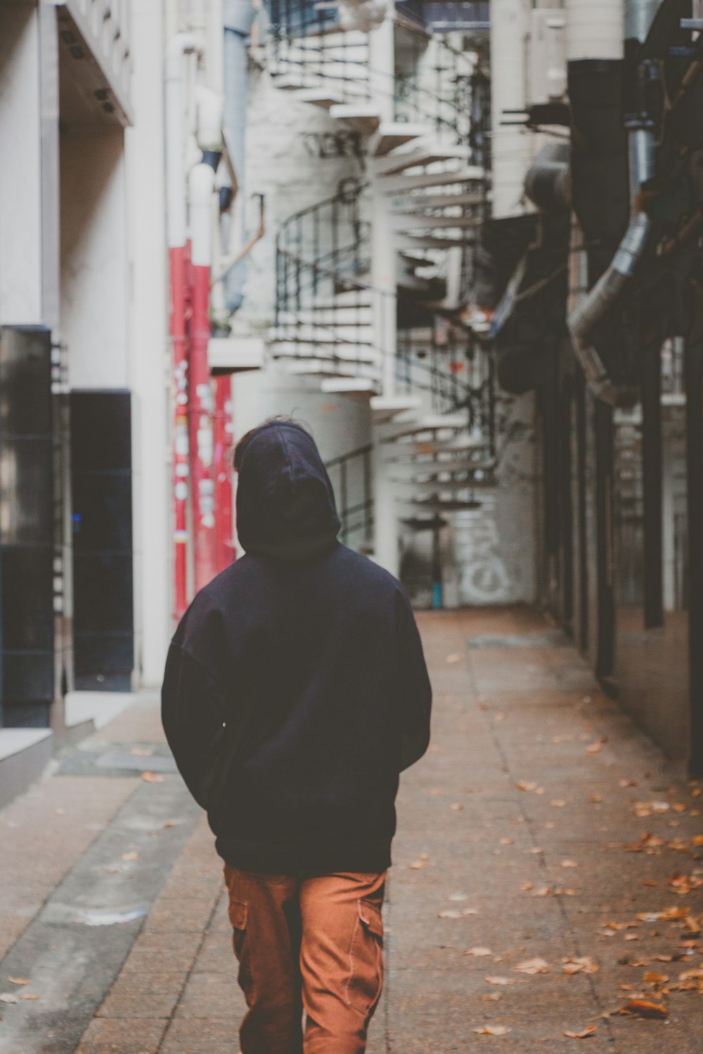 a man walking down a sidewalk next to a tall building