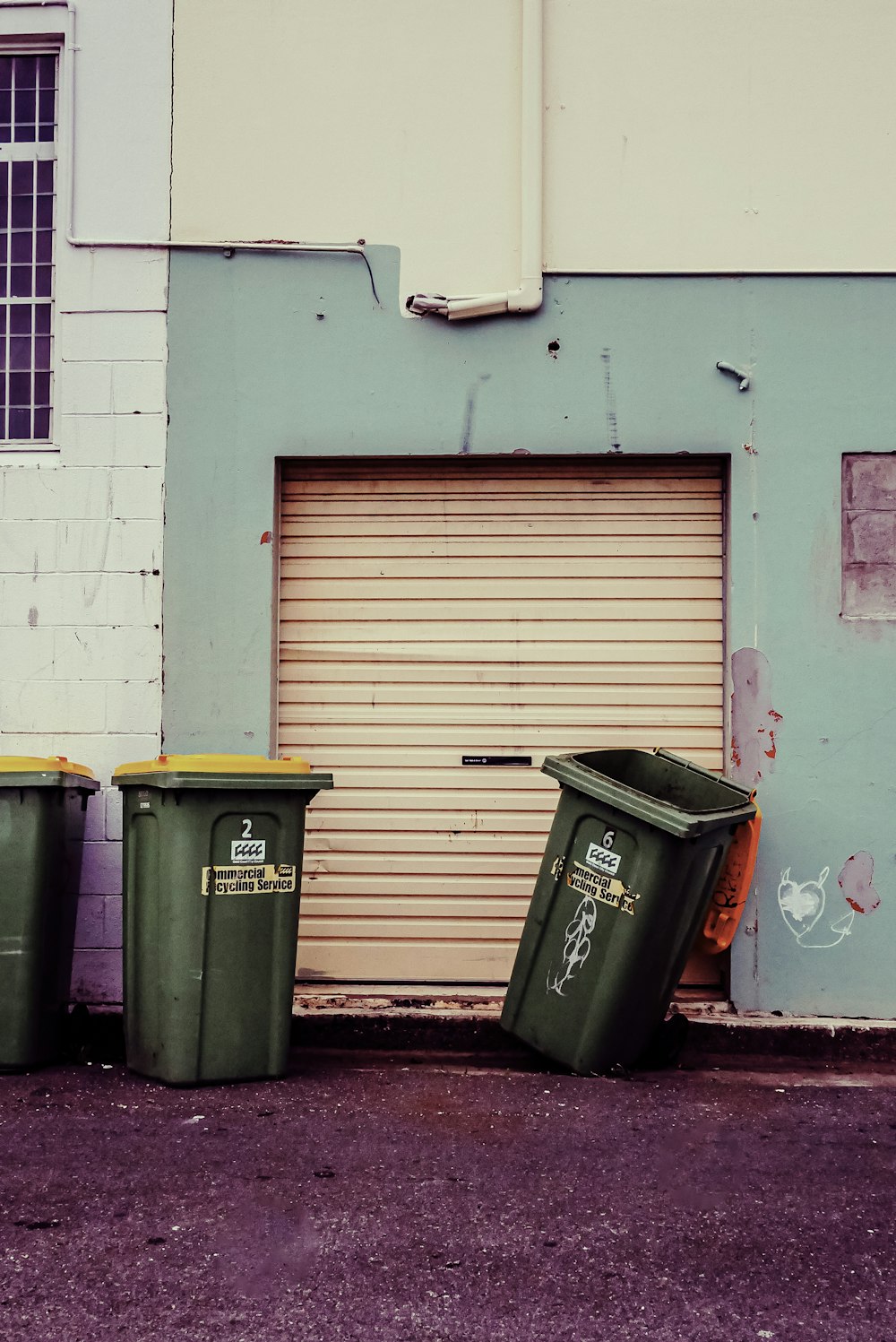 three trash cans sitting in front of a garage door