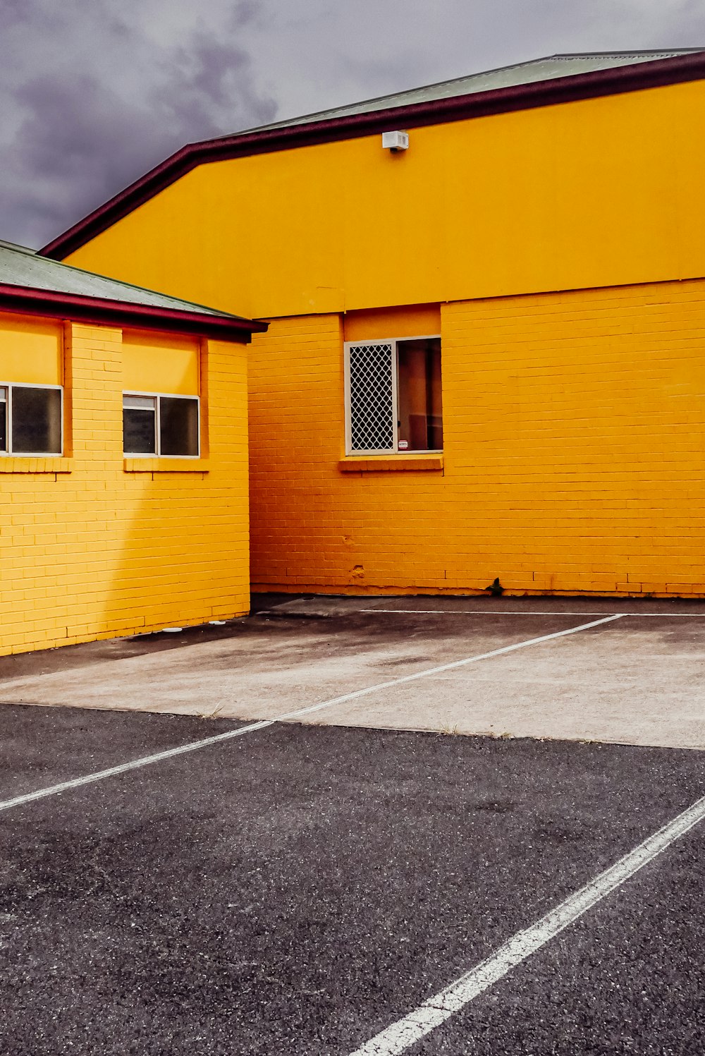 an empty parking lot with a yellow building in the background