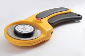 a yellow and black tool on a white surface
