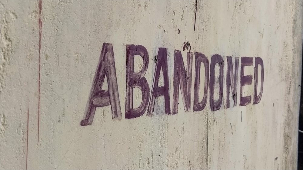 un panneau indiquant abandonné sur un mur de béton