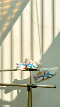 A pair of tri-star sneakers resting on a wooden bench with sunlight filtering through leaves