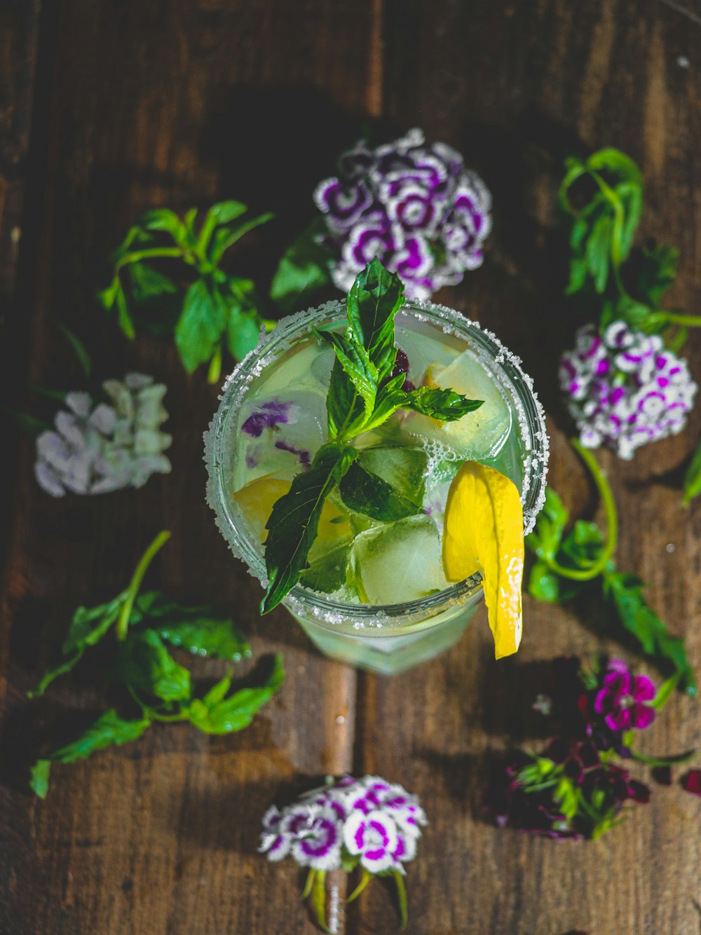 a drink with a lemon wedge and a green garnish