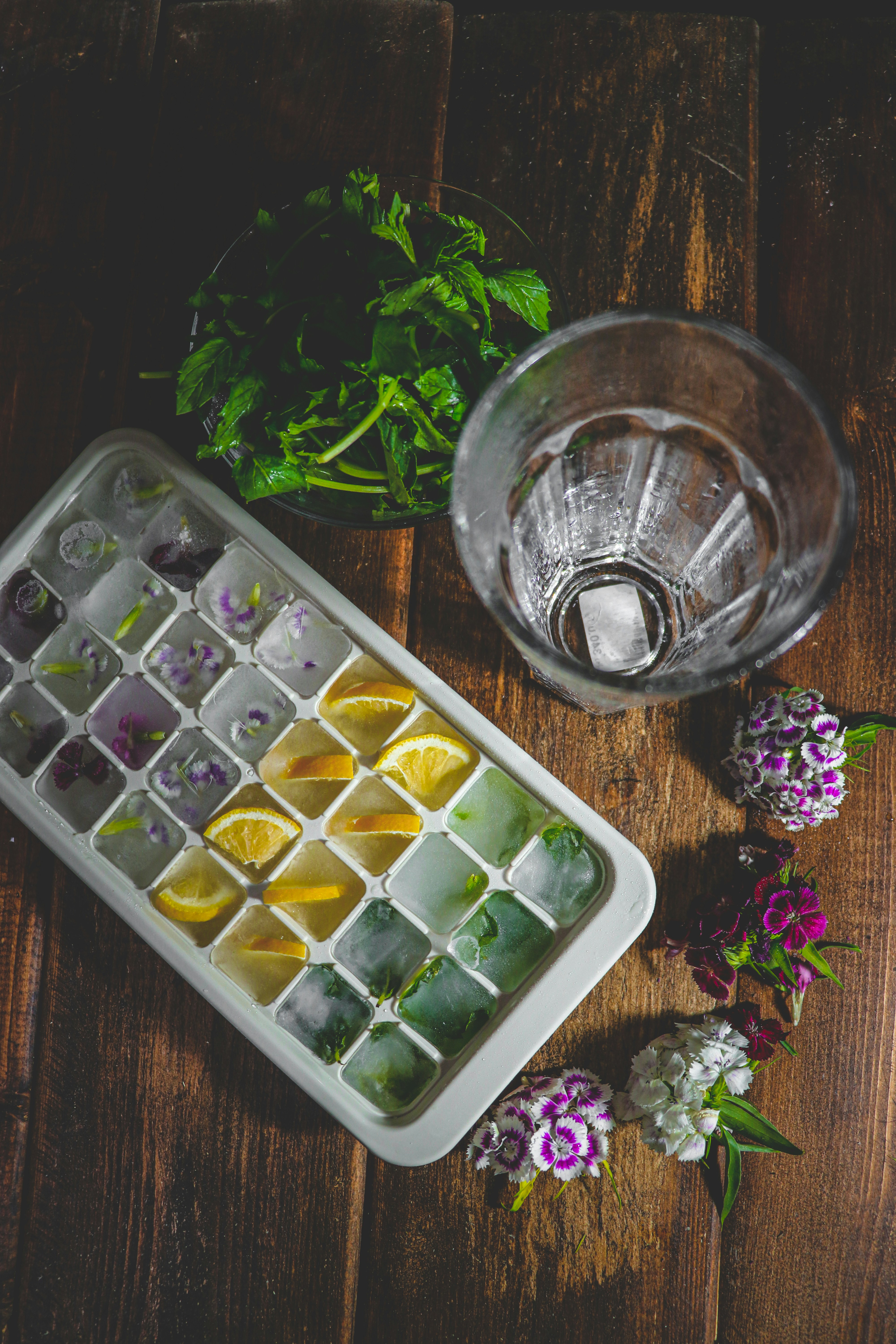 a tray of ice cubes next to a glass of water