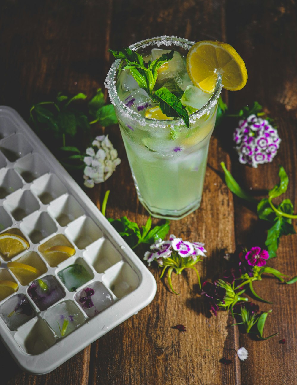 a glass of lemonade with ice cubes and flowers
