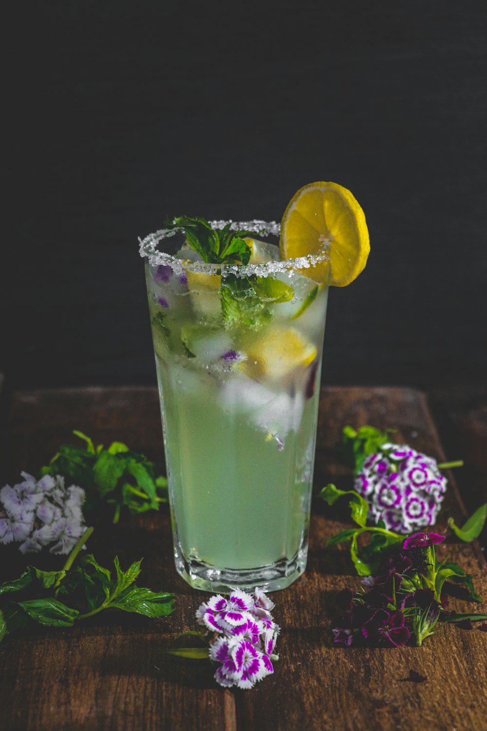 a tall glass filled with a green drink and a slice of lemon