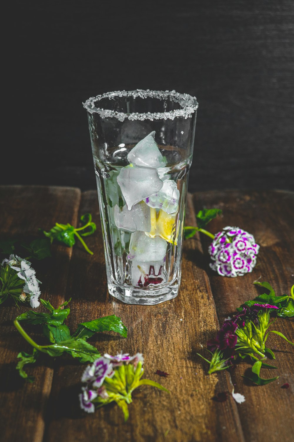 a glass filled with ice sitting on top of a wooden table