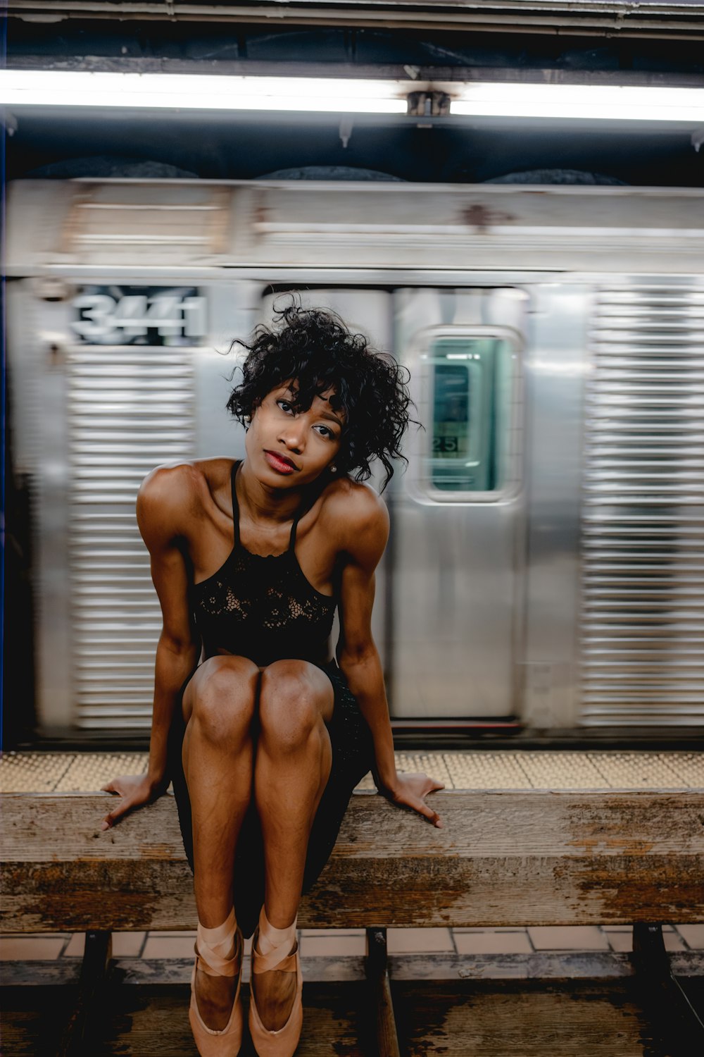 a woman sitting on a bench in front of a train