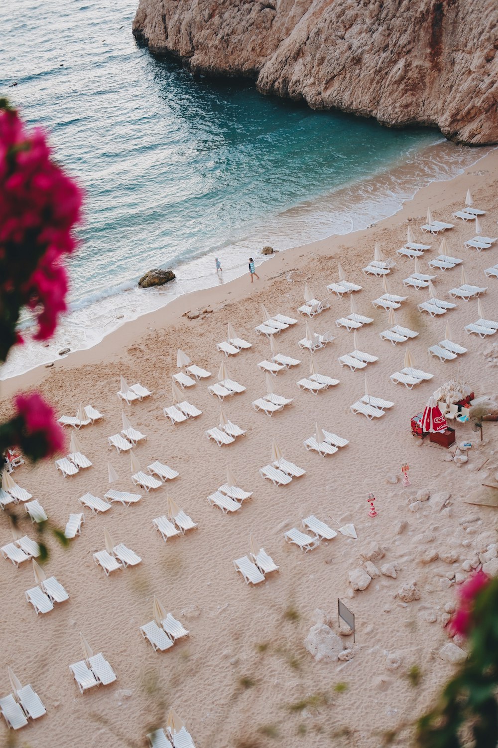 uma praia de areia com muitas cadeiras e guarda-sóis