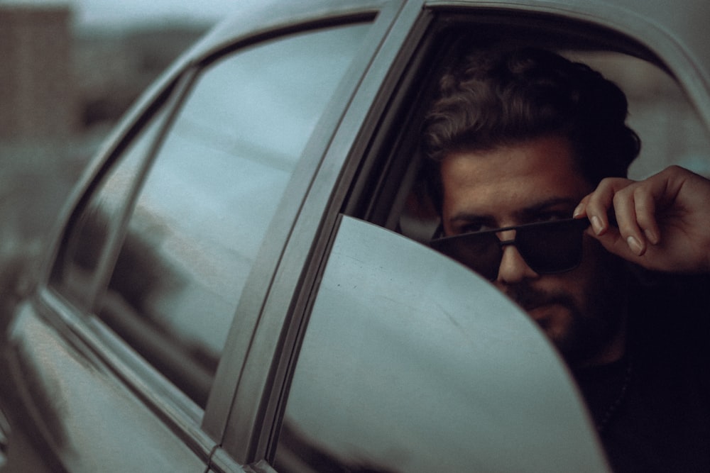 a man wearing sunglasses looking out of a car window