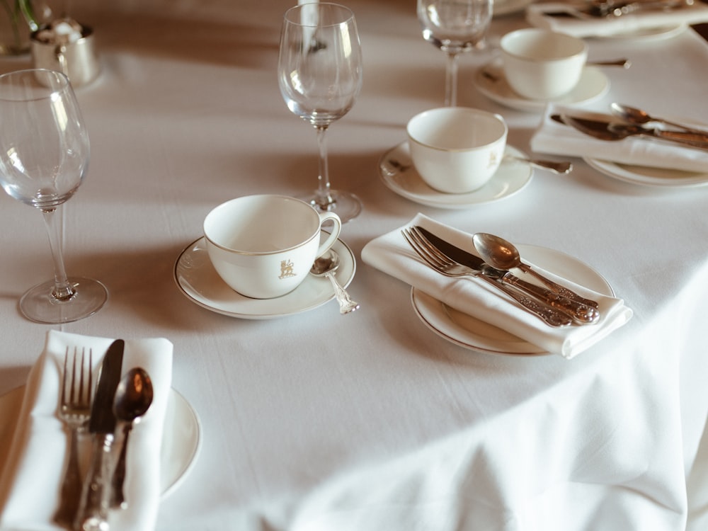 a table set with silverware and wine glasses