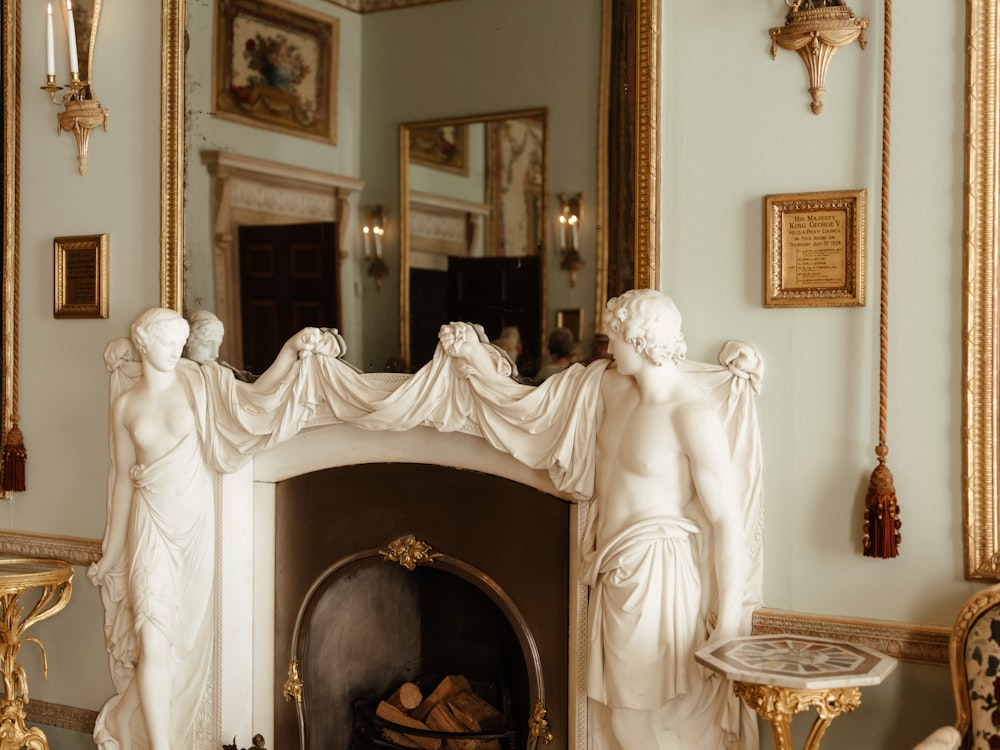 a fireplace with statues and a mirror in a room
