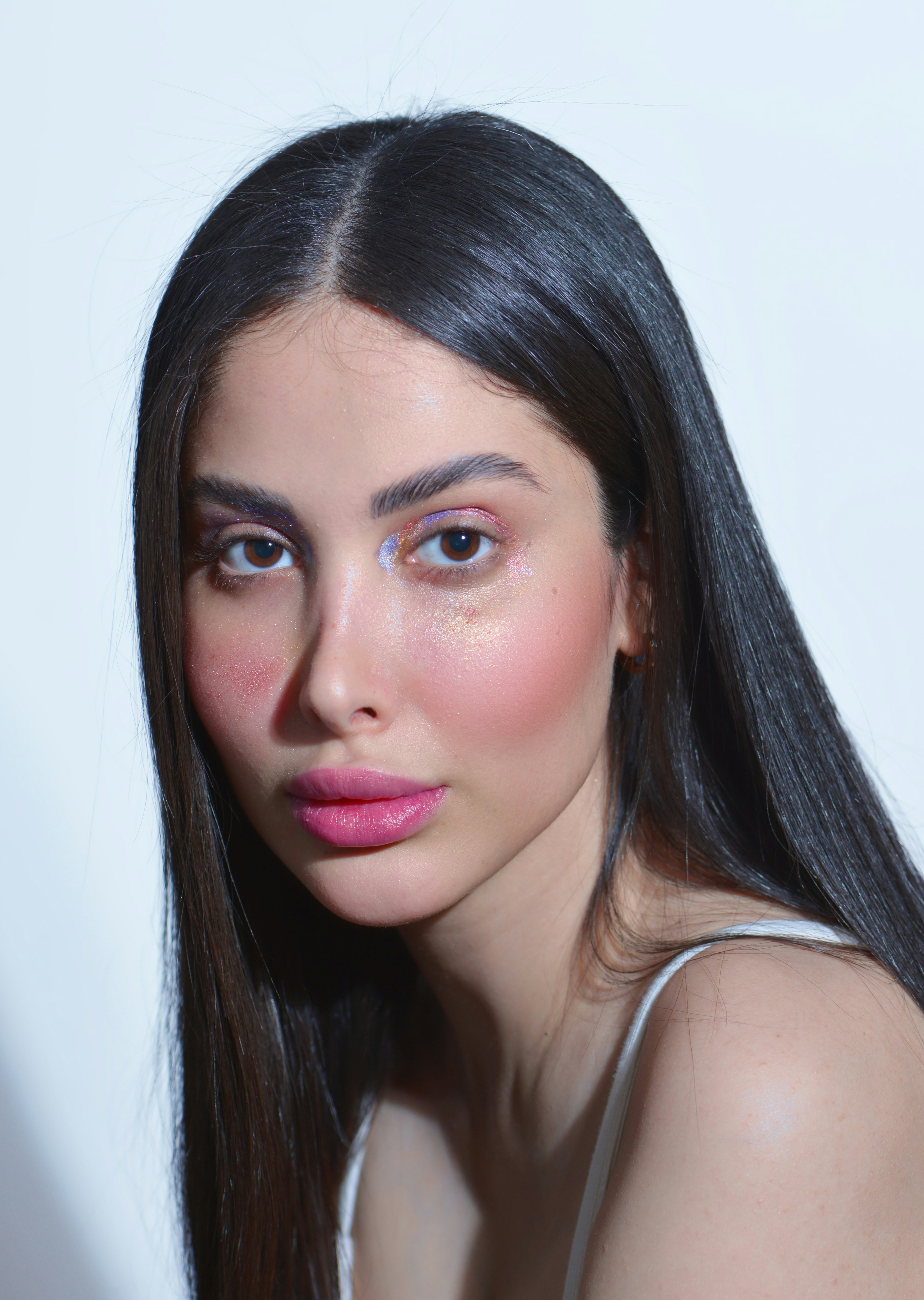 a woman with long black hair wearing a white tank top