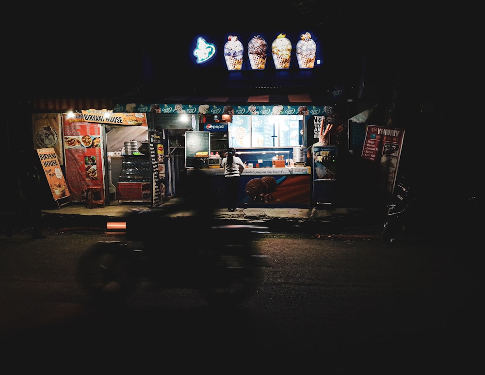 a dark street at night with a food stand lit up