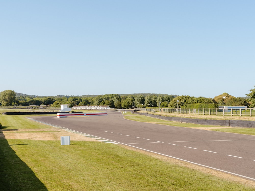 an empty road in the middle of a grassy field