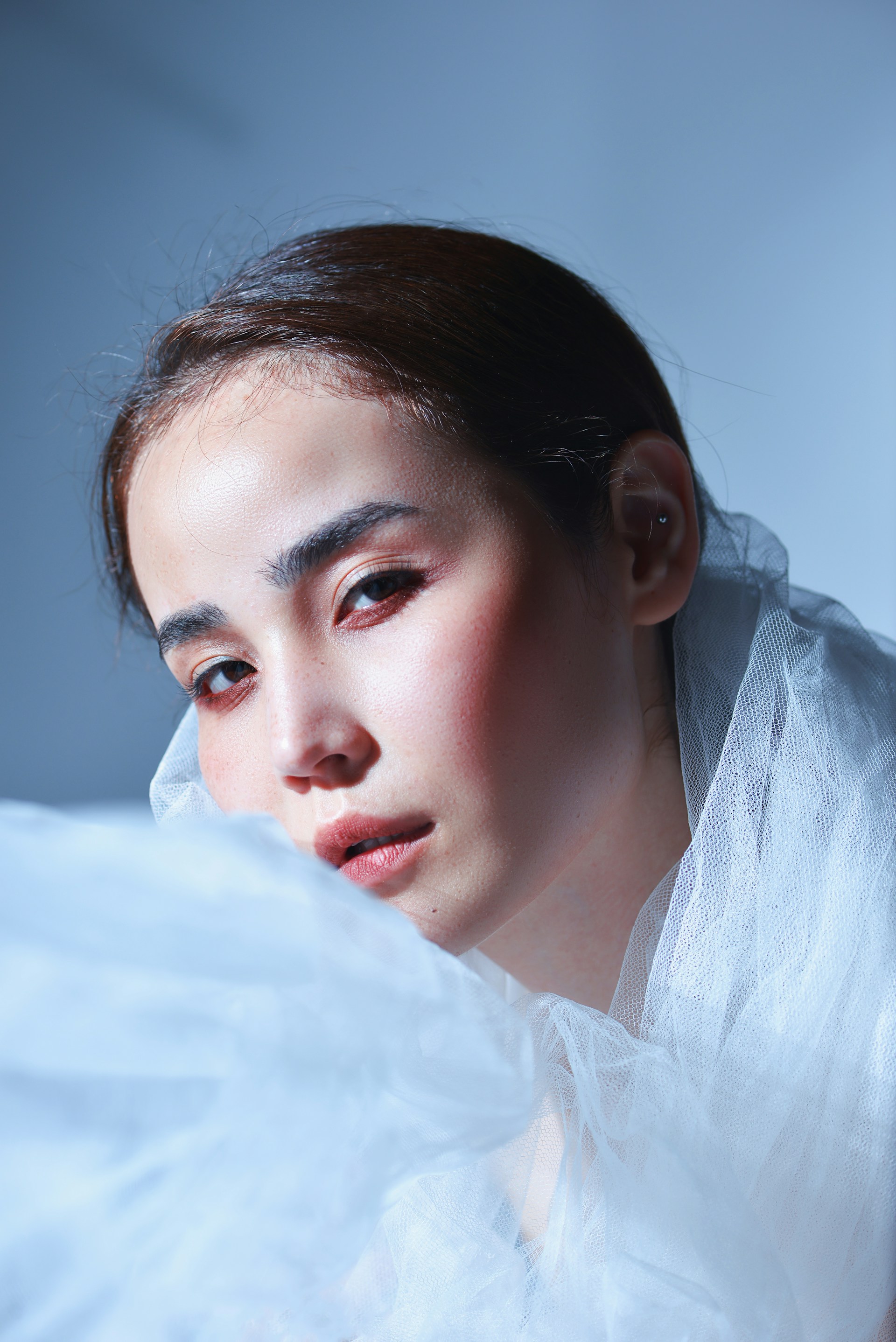 A close-up of Shadowsylph's face, framed by wisps of silver hair and dark green makeup, capturing an ethereal, ghostly expression.
