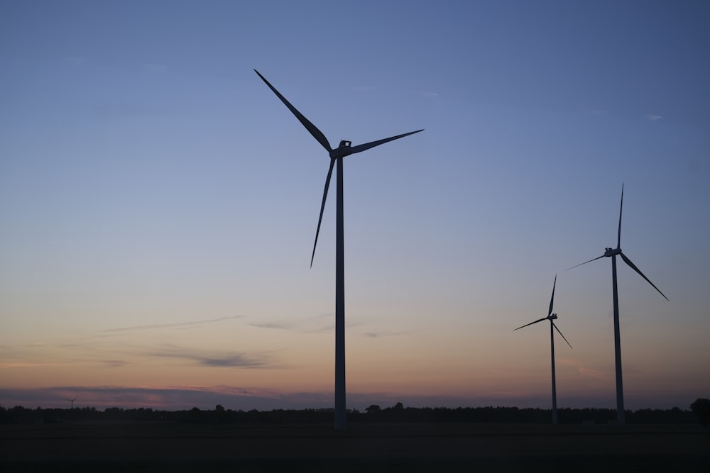 Eine Gruppe von Windmühlen zeichnet sich vor einem blauen Himmel ab