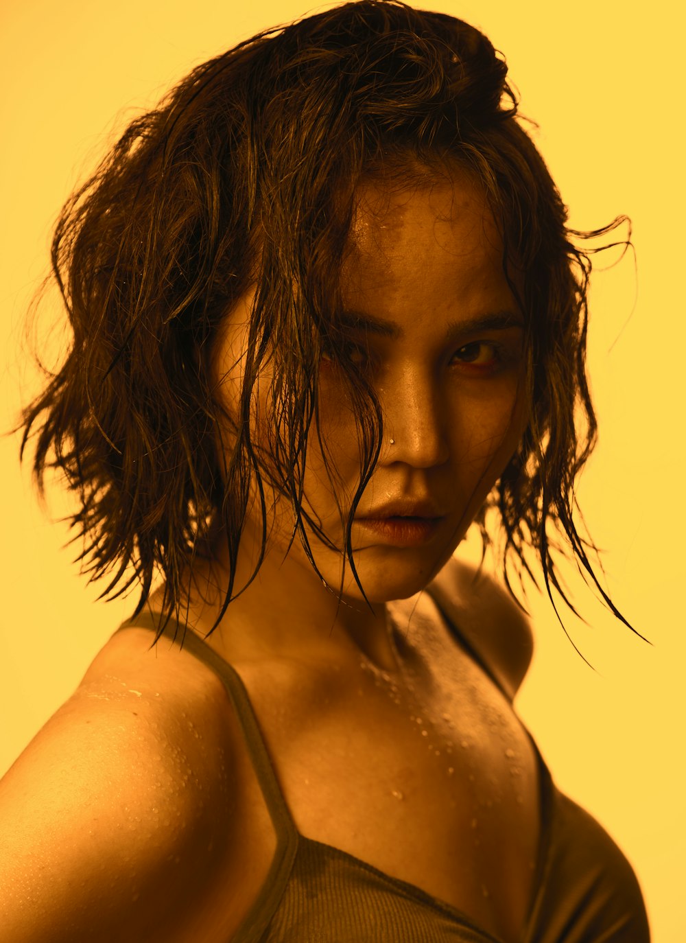 a woman with wet hair standing in front of a yellow background