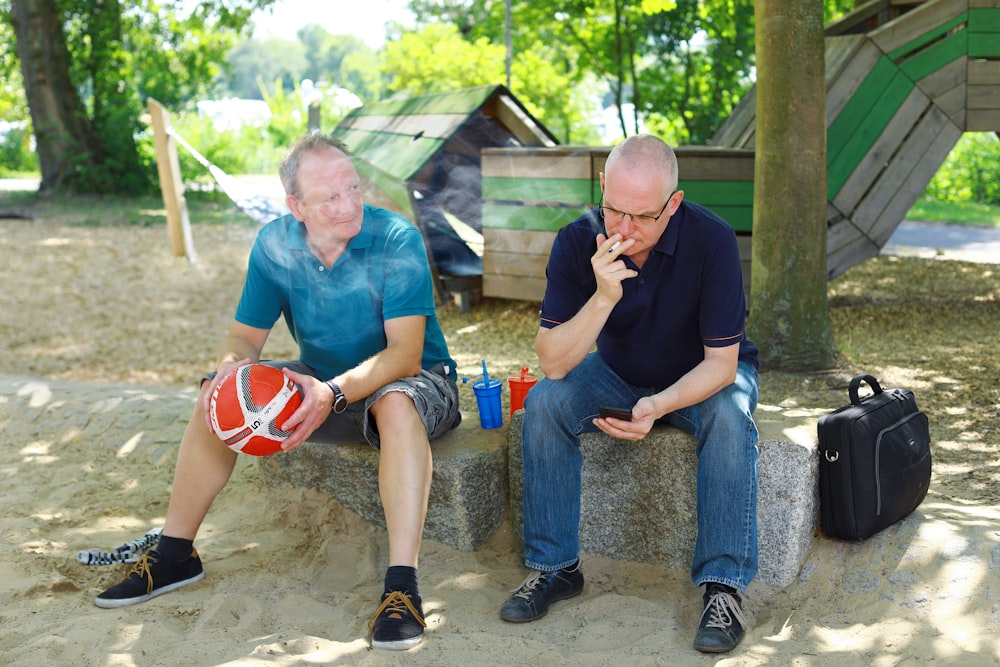 a couple of men sitting on top of a cement bench