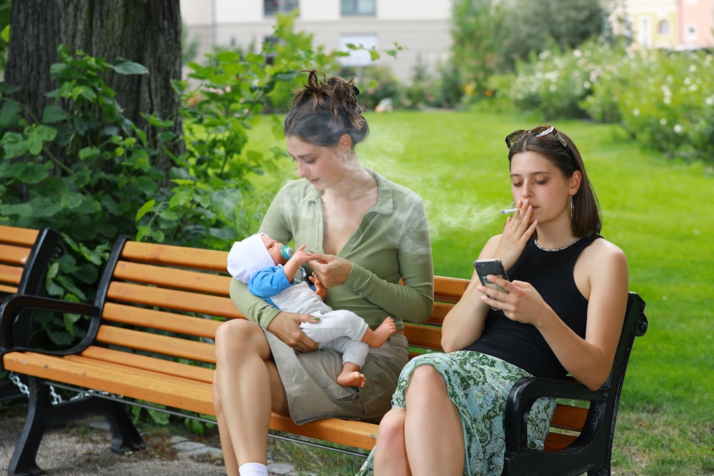 two women sitting on a bench with a baby
