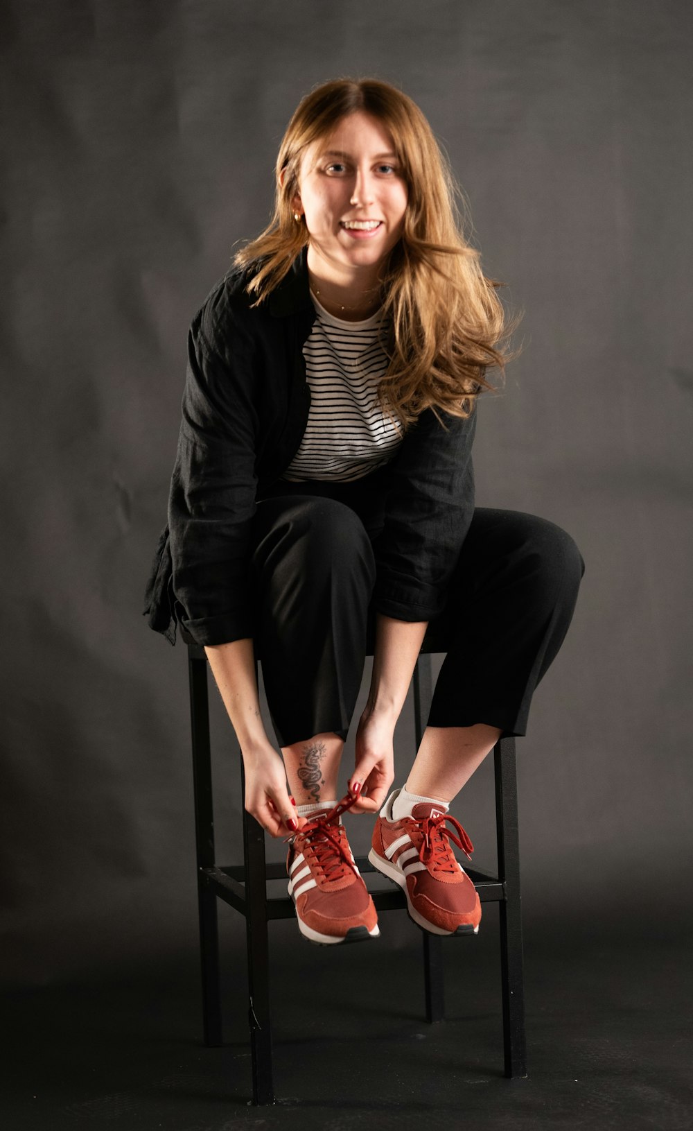 a woman sitting on top of a chair holding a pair of red shoes