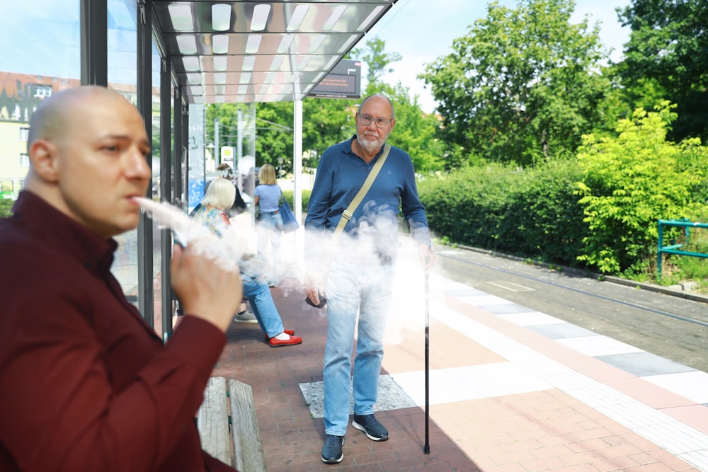 a man smoking a cigarette in front of a bus stop