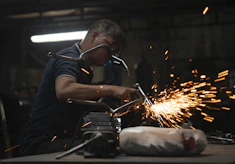 A skilled technician welding a ship's hull under bright workshop lights.