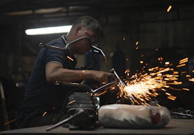 A skilled technician welding a ship's hull under bright workshop lights.