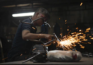 Skilled technician welding metal components in an industrial workshop with sparks flying.
