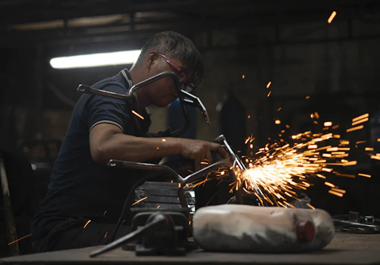 Skilled worker welding a metal frame with sparks flying in a modern workshop.