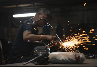 A skilled welder carefully assembling metal parts in a bright, modern industrial workshop.