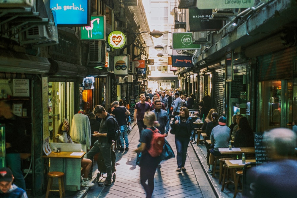 a group of people walking down a street next to tall buildings