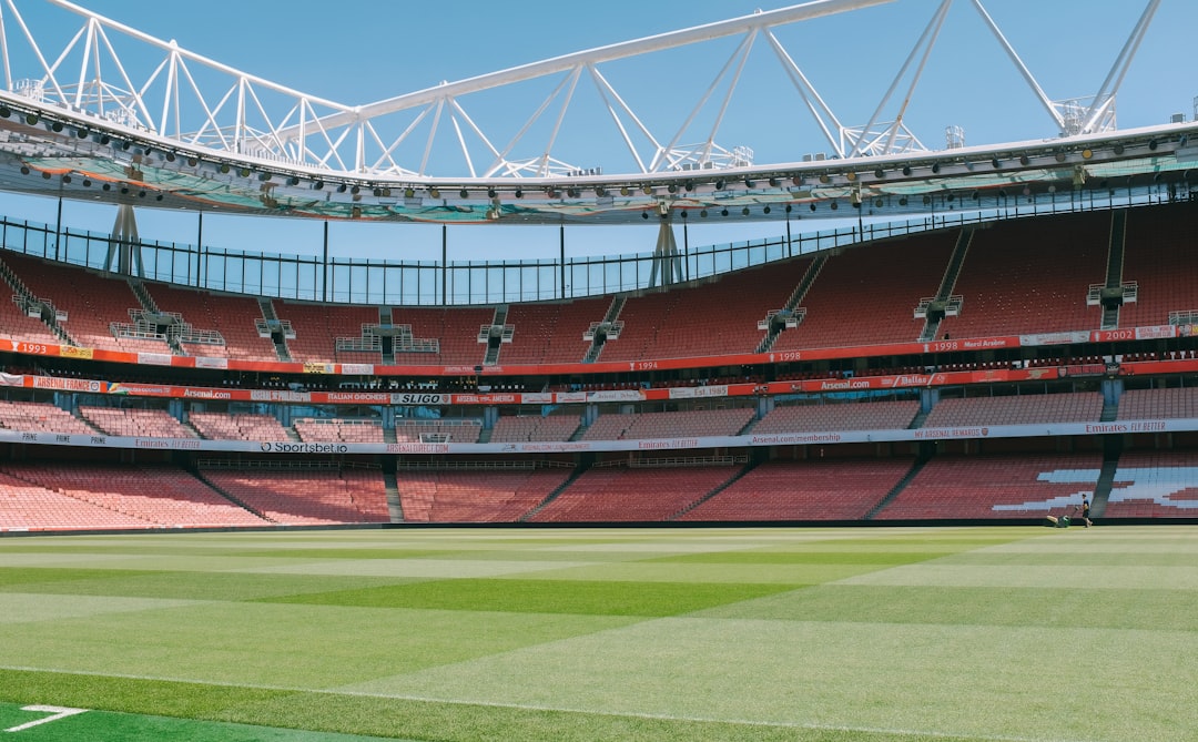 an empty stadium with a green field and red seats,