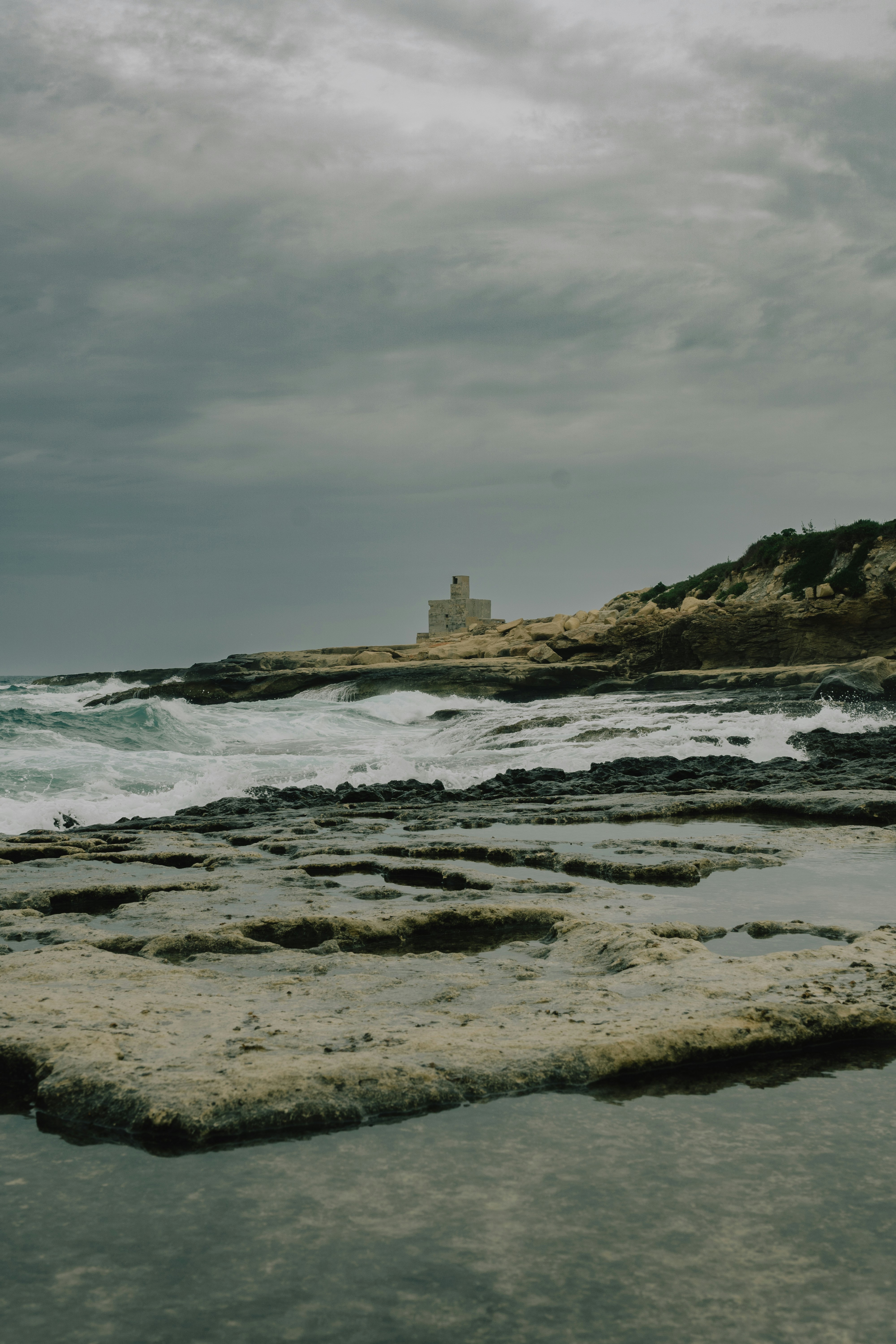a rocky beach with a lighthouse in the distance