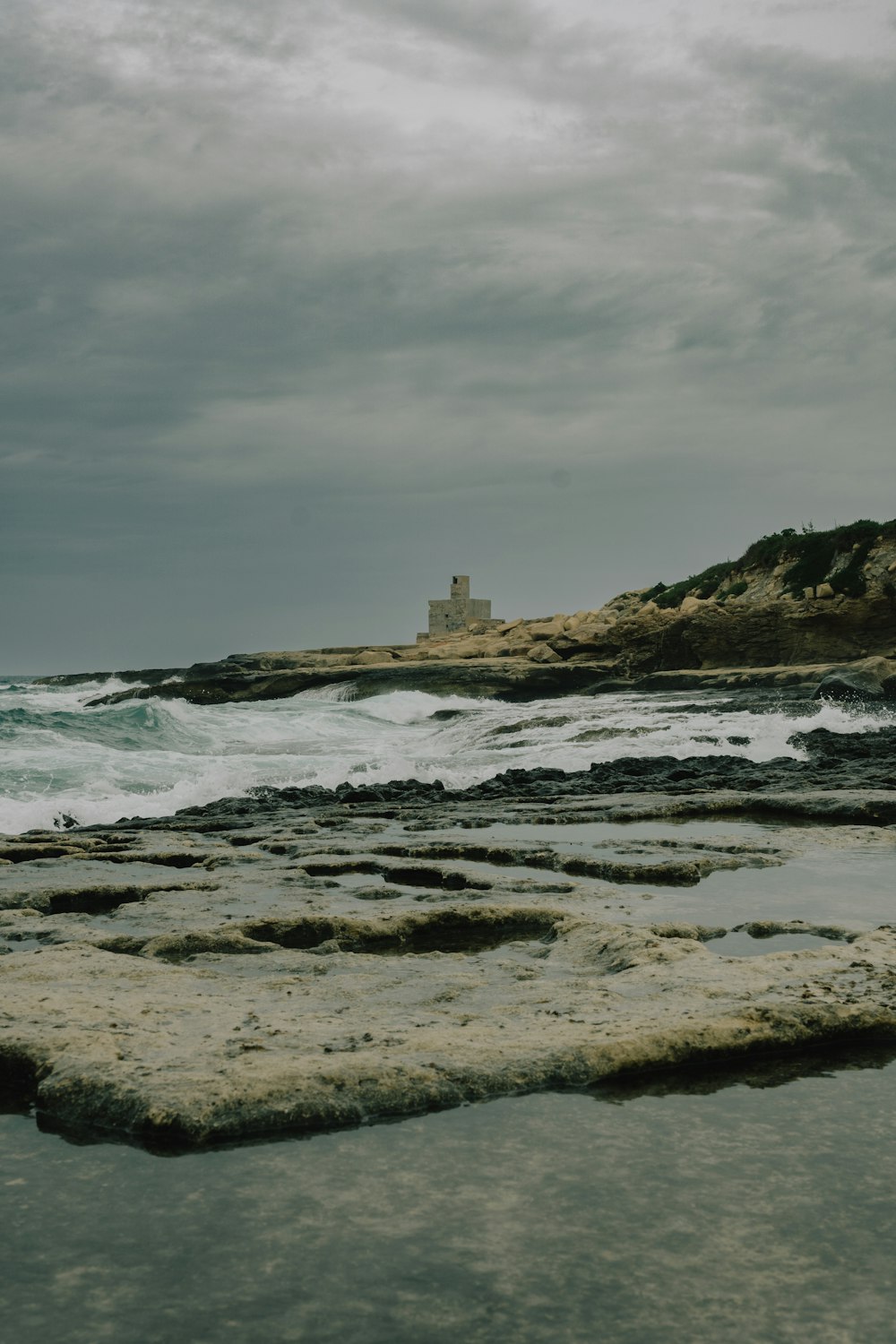 a rocky beach with a lighthouse in the distance