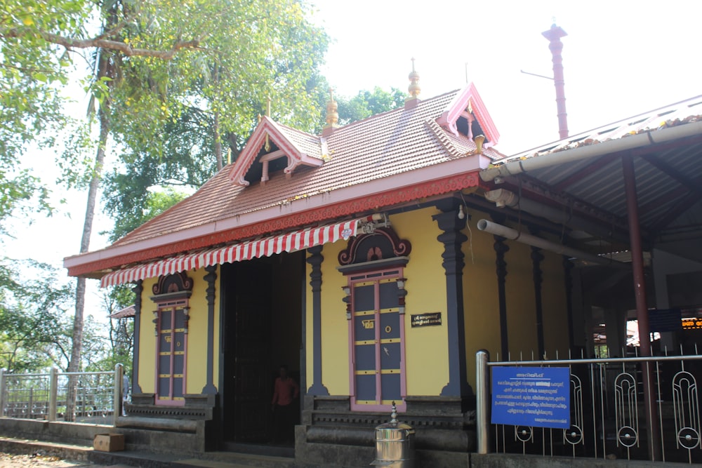 a small yellow and red building with a red roof