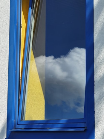 A modern white aluminum window frame installed in a bright living room with blue accents.