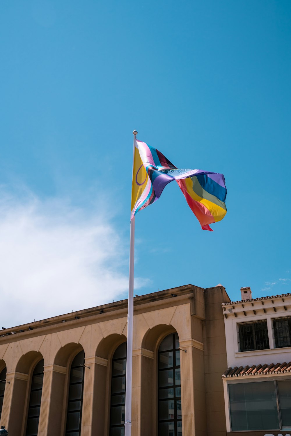 a colorful flag is flying in front of a building