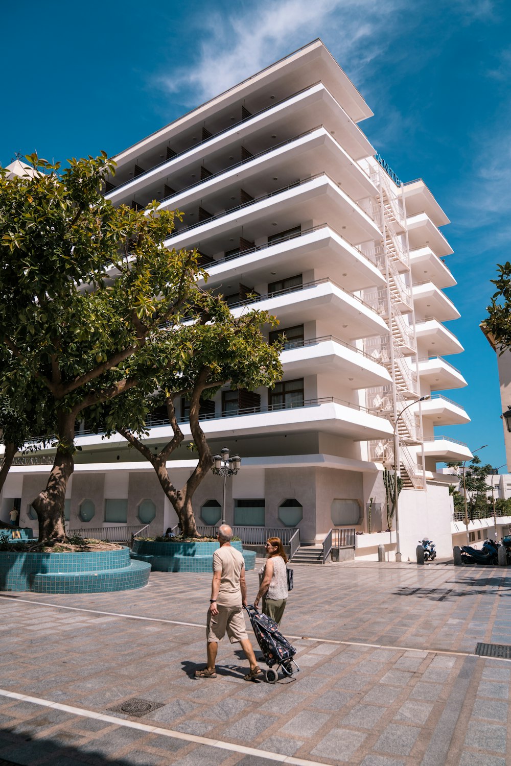 a couple of people walking down a sidewalk near a building