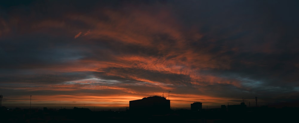 a sunset with clouds and buildings in the background