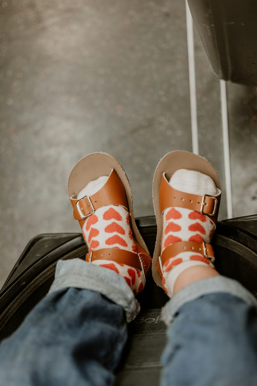 a person's feet in sandals sitting on top of a piece of luggage