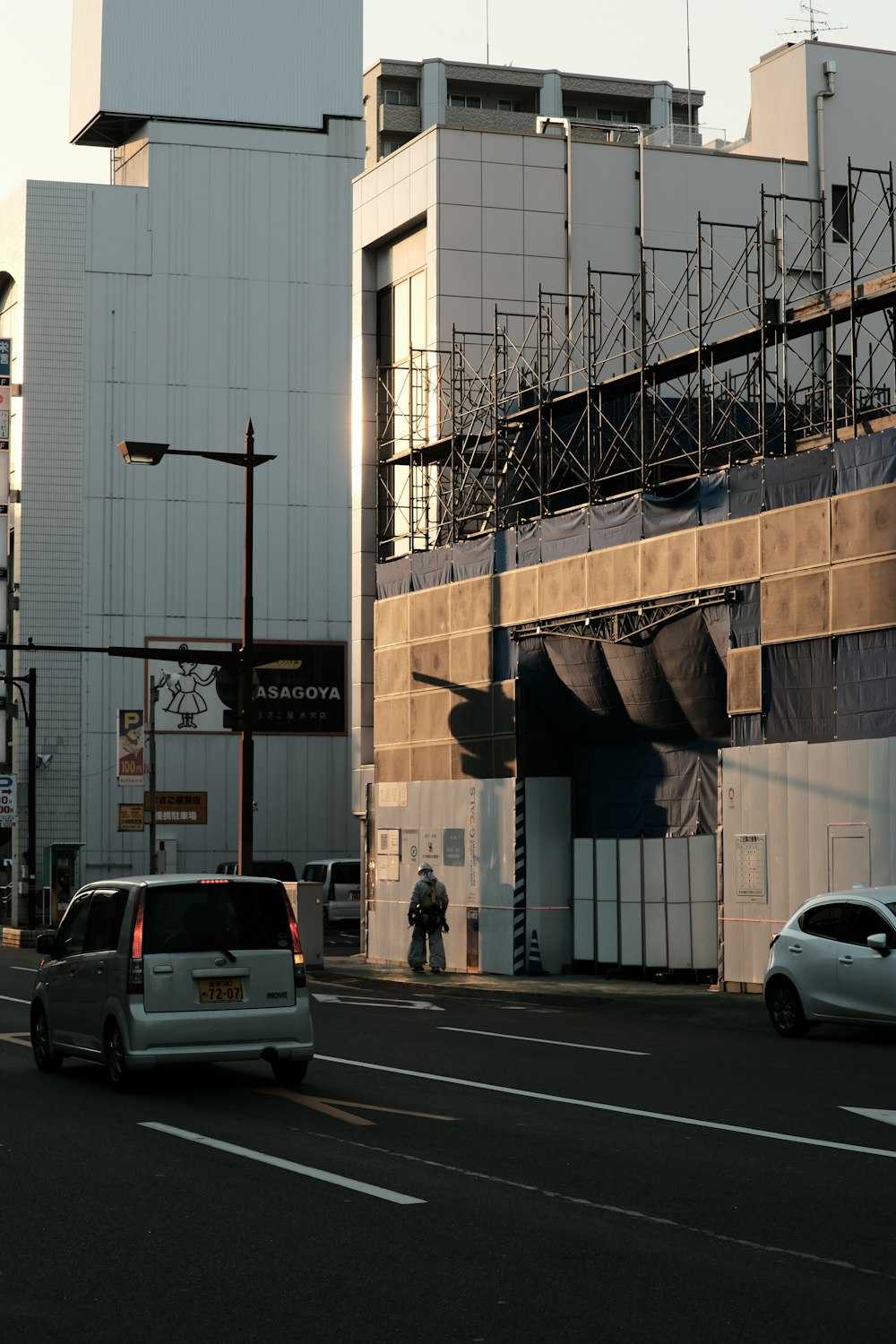 a city street with cars and scaffolding on a building