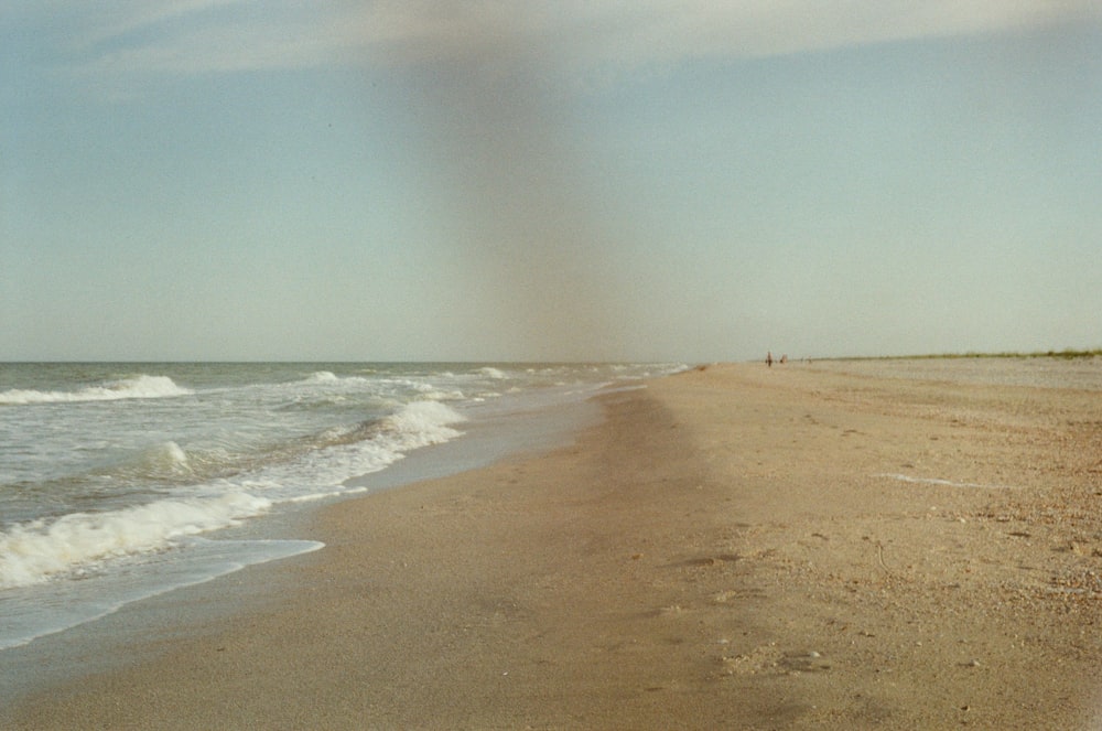 uma praia de areia com ondas entrando na costa