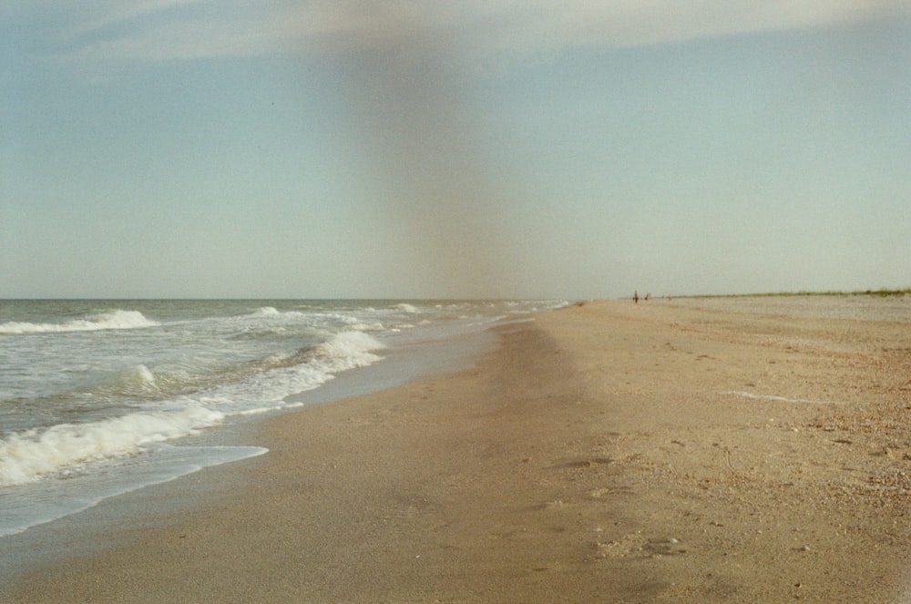 a sandy beach with waves coming in to shore